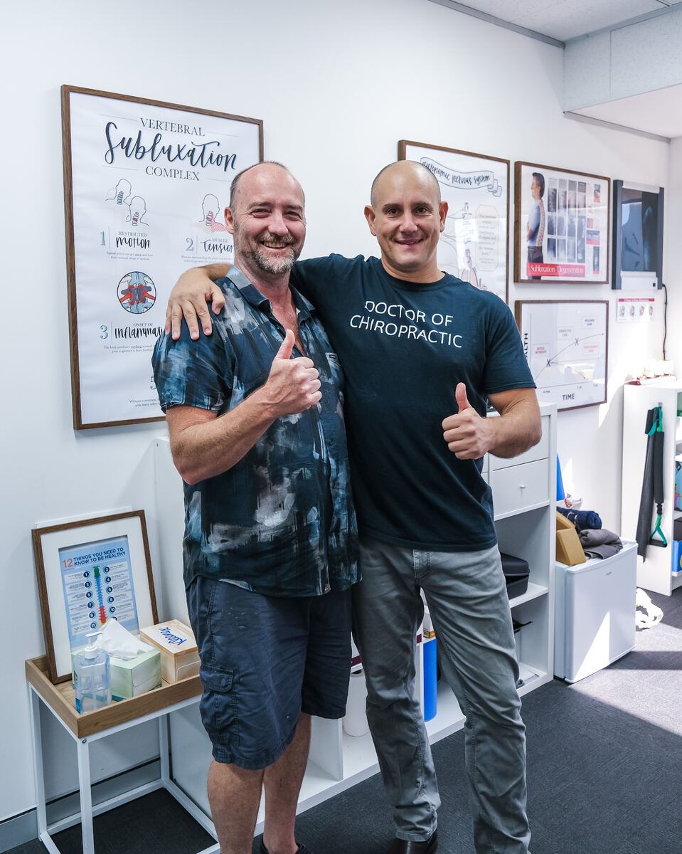 Happy patient with chiropractor giving thumbs up
